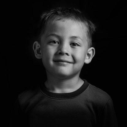 a cute smiling boy / as portrayed in black and white / a cute smiling boy