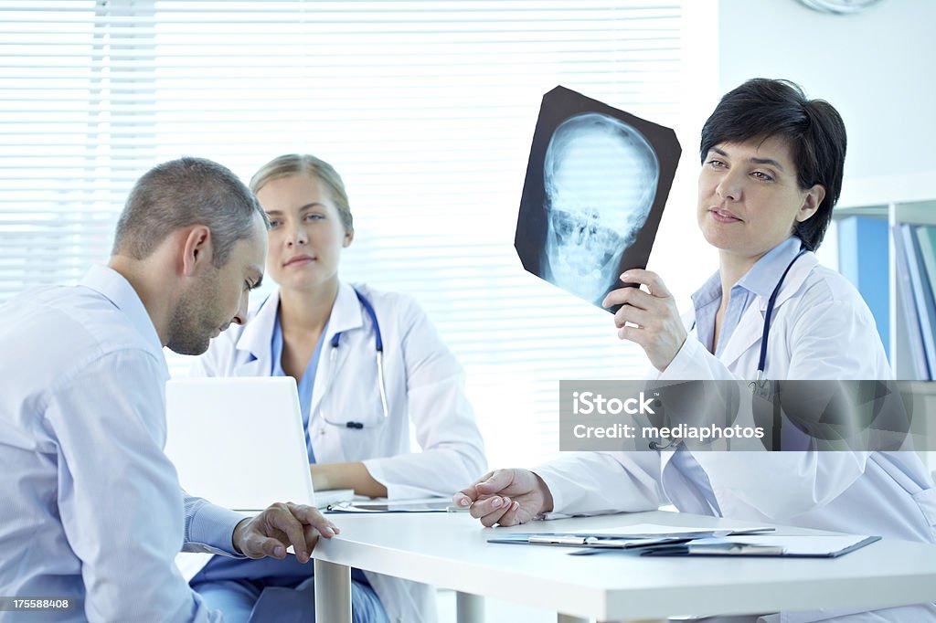 Examining scull x-ray Female clinician showing skull x-ray to her patient 20-24 Years Stock Photo