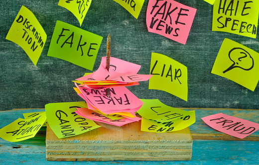Fight against fake news concept,sticky notes with fake news topics spiked on a nail, focus on forground,close up,