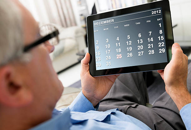 Man holding a digital tablet with December 2012 calendar Man holding a digital tablet with December 2012 calendar calendar 2012 stock pictures, royalty-free photos & images