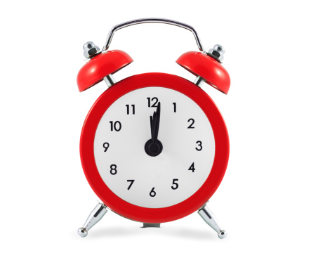 Red alarm clock showing 12 O'Clock