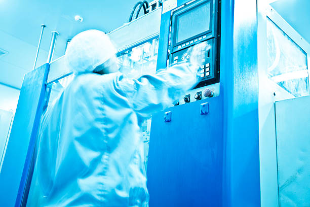 clean room in pharmaceutical factory clean room in pharmaceutical factory with technician in blueclean room in pharmaceutical factory with technician in blue pharmaceutical manufacturing machine stock pictures, royalty-free photos & images