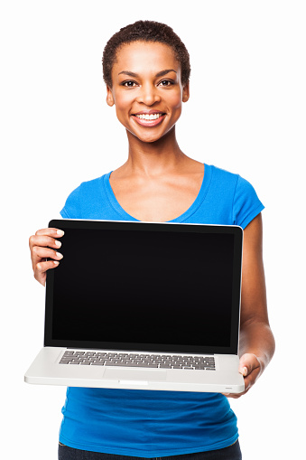 Portrait of a cheerful African American woman holding laptop with blank screen. Vertical shot. Isolated on white.