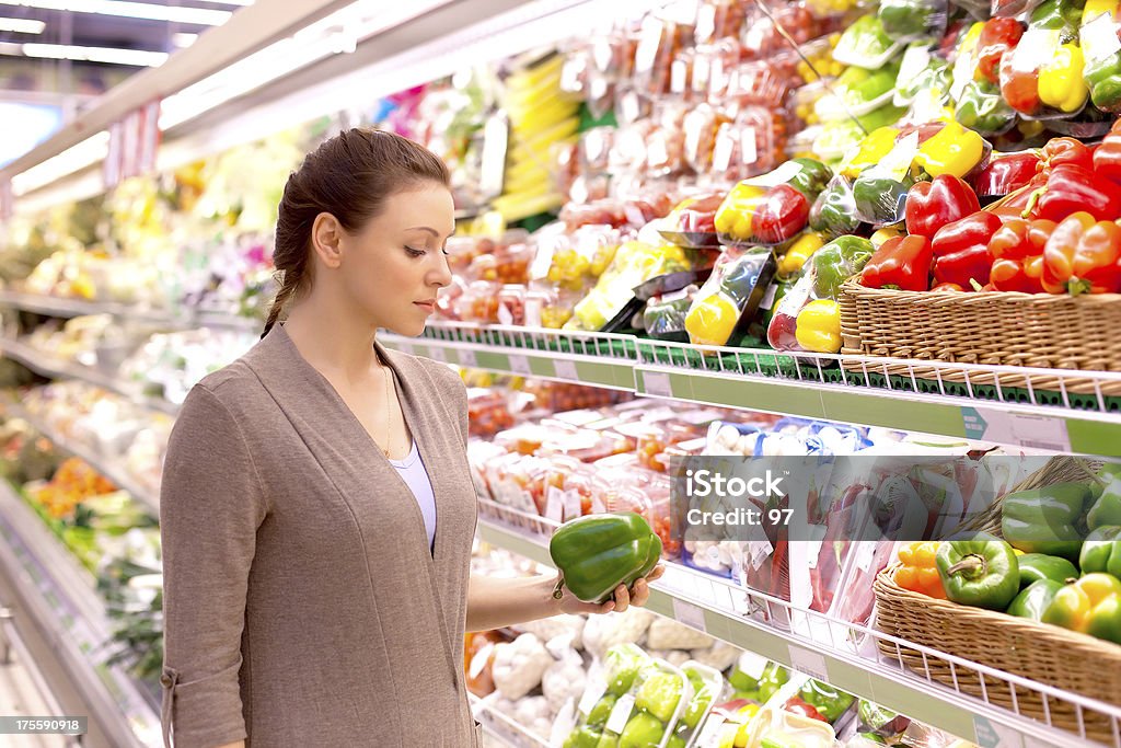 A mulher com muita atenção considera produtos hortícolas na loja - Royalty-free Loja de Comida Saudável Foto de stock