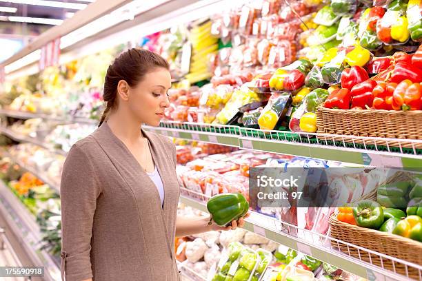 A Mulher Com Muita Atenção Considera Produtos Hortícolas Na Loja - Fotografias de stock e mais imagens de Loja de Comida Saudável