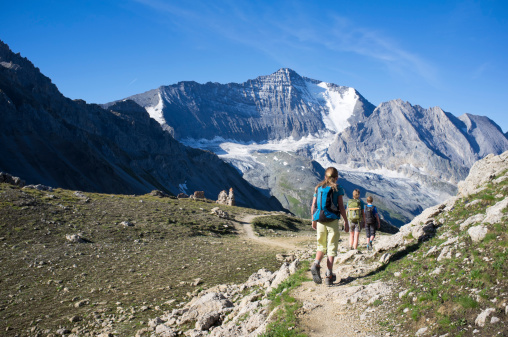 A mother and her two children walking a high altitude route in the France Alpes.
