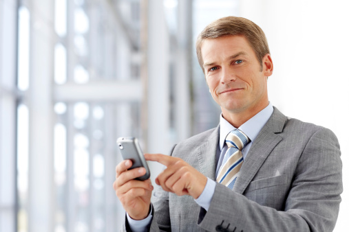 Portrait of mid adult male business manager pointing at his cell phone. Horizontal shot.