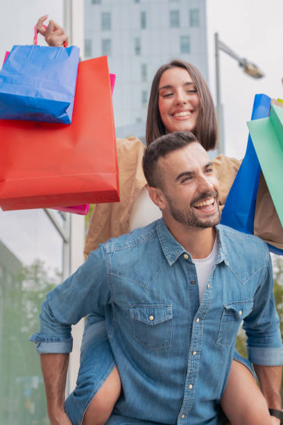 istock Man carrying his girlfriend on his back having fun with shopping bags 1755917638