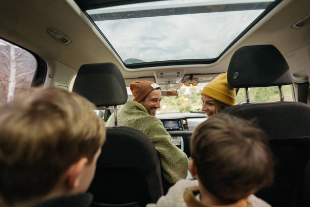 Ready for an autumn adventure? Photo of a smiling, cheerful family sitting in their car, all packed up and ready for an autumn adventure car interior stock pictures, royalty-free photos & images