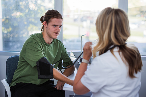 Young man sitting at a doctor's office and having his blood pressure checked