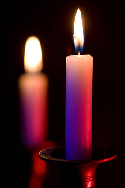 Two candles burn highlighted by contrasting blue and red lights.  Shallow Depth of Field adds softness to the image.