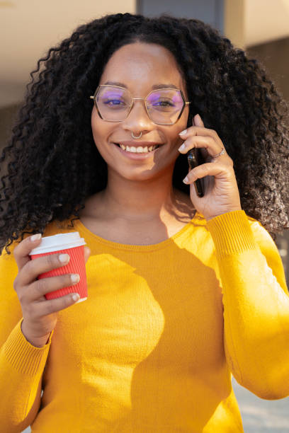 istock Close-up portrait smiling black woman at mobile phone while drinking coffee. 1755949403