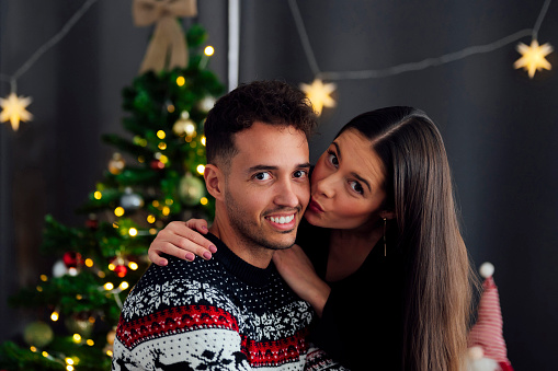 Happy young couple kissing at home on christmas