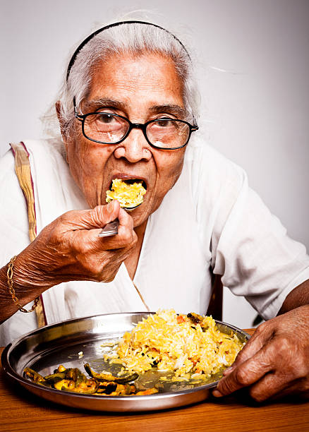 istock One senior Indian woman having food 175596131