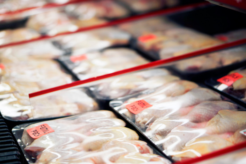 Packaged chicken legs in store refrigerator.