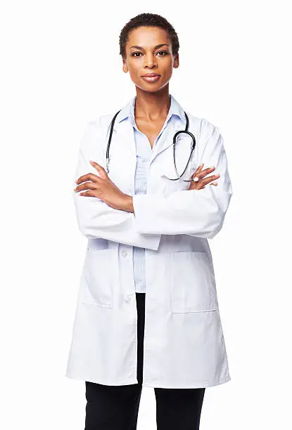 Portrait of a confident African American female doctor standing with arms crossed. Vertical shot. Isolated on white.