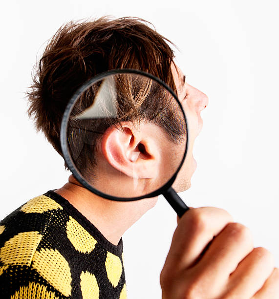 istock Zany young man with magnifying glass over ear 175596393
