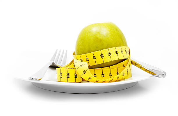 ernährung - healthy eating fork tape measure still life stock-fotos und bilder