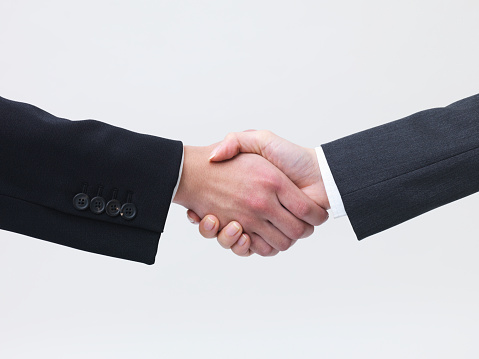 Business manager does handshake with a new employee during a briefing meeting, welcoming her to the team and presenting her to other staff members. Young man shaking hands with trainee. Camera A.