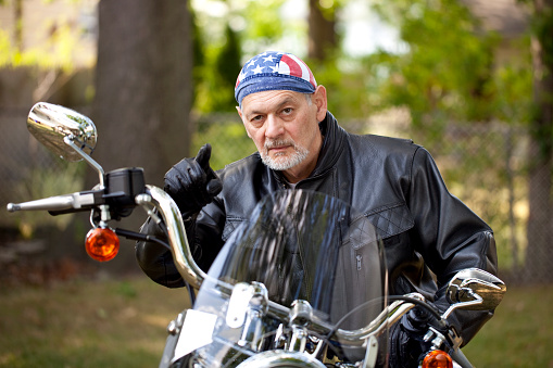Angry Biker in leather jacket sitting on motorcycle pointing toward camera with menacing look on his face. Image shot with, Canon 5D Mark2, 100 ISO, 24-115mm lens