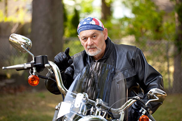 Angry Biker in leather jacket on motorcycle pointing toward camera Angry Biker in leather jacket sitting on motorcycle pointing toward camera with menacing look on his face. Image shot with, Canon 5D Mark2, 100 ISO, 24-115mm lens do rag stock pictures, royalty-free photos & images
