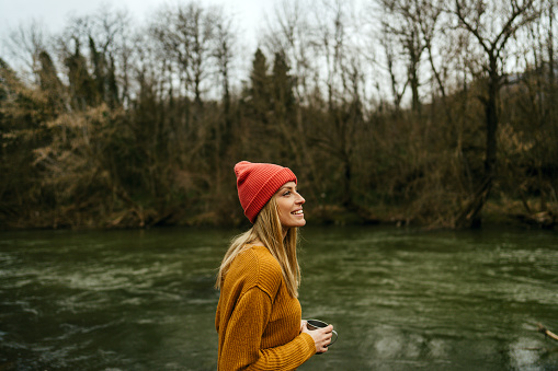 Photo of a mid adult woman spending her extended weekend in nature, on the properti that's over looking on a beautiful river