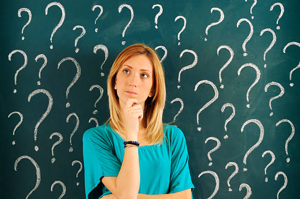 Young woman is thinking about many questions. She is chosing the best one of all which she is pointing with her finger.