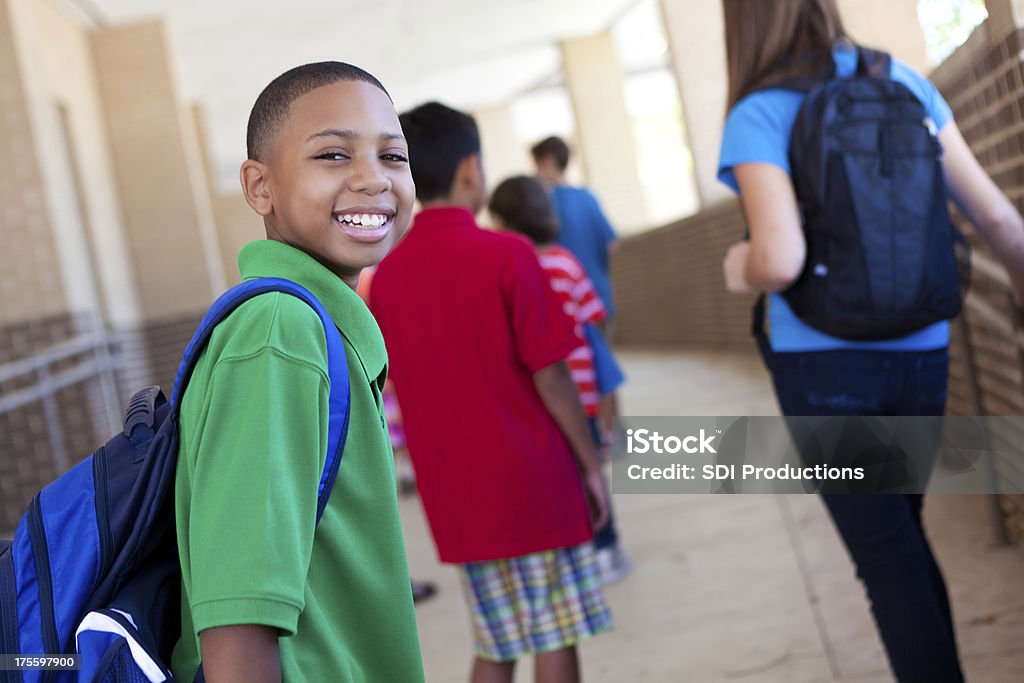 Улыбающегося молодой Мальчик в школе с другими студентов - Стоковые фото Рюкзак роялти-фри
