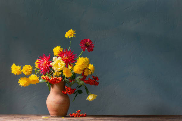 istock red and yellow flowers on jug in sunlight on background dark wall 1755980778