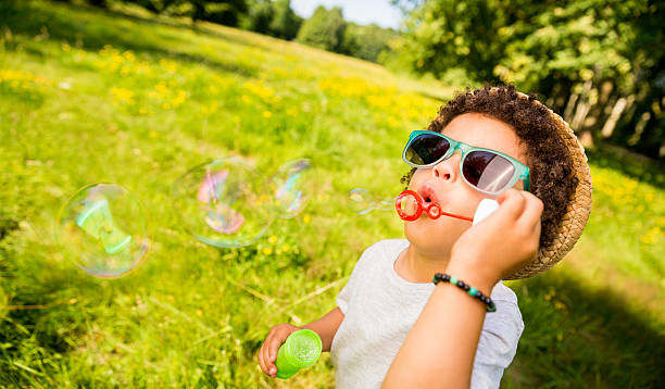 istock Little african american boy blowing bubbles in park 175598421