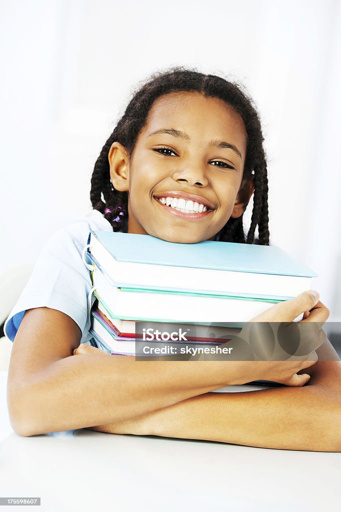 Sorridente giovane studentessa accogliere pila di libri. - Foto stock royalty-free di Abbracciare una persona