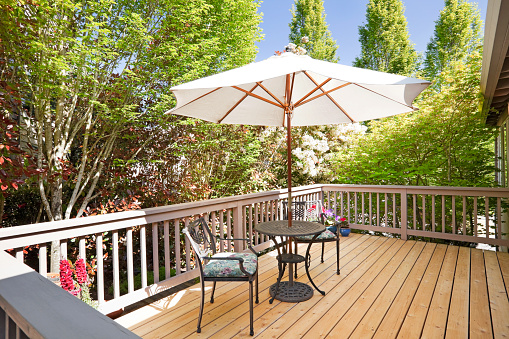 Sunny back deck with table, chairs, and umbrella.