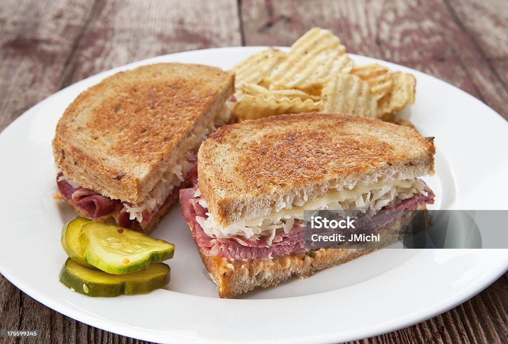 Reuben Sandwich Reuben sandwich with chips and pickles on a rustic wood table. Reuben Sandwich Stock Photo
