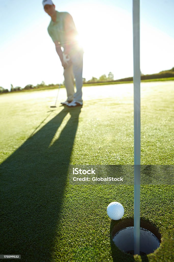 Patience is key Mature male golfer putting towards the hole on the green - focus on the foreground Golf Stock Photo