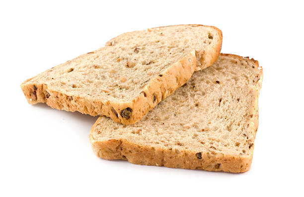dwa plasterki brązowy chleb razowy na białym tle - baked bread brown carbohydrates zdjęcia i obrazy z banku zdjęć
