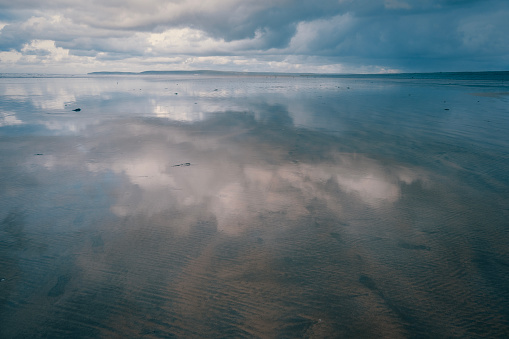 Reflections of sea and sky in the retreating tide on a beach in Devon
