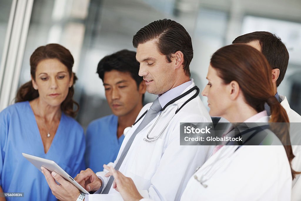 Using modern wireless technology to their advantage A full medical team going over a patient's chart on a digital tablet Adult Stock Photo