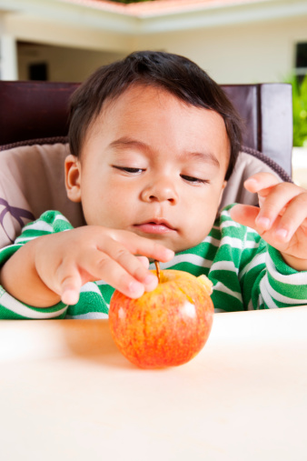 A little Latino boy getting ready to eat an apple