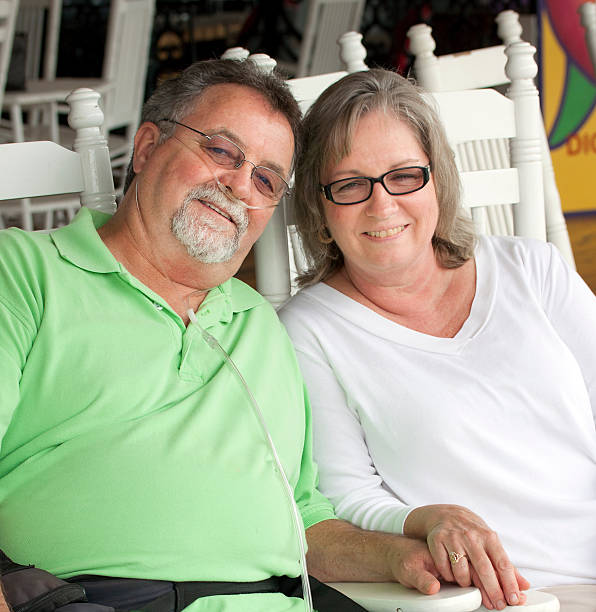 Happy senior couple sitting in white wooden chairs A smiling senior couple, man with oxygen equipment. medical oxygen equipment stock pictures, royalty-free photos & images