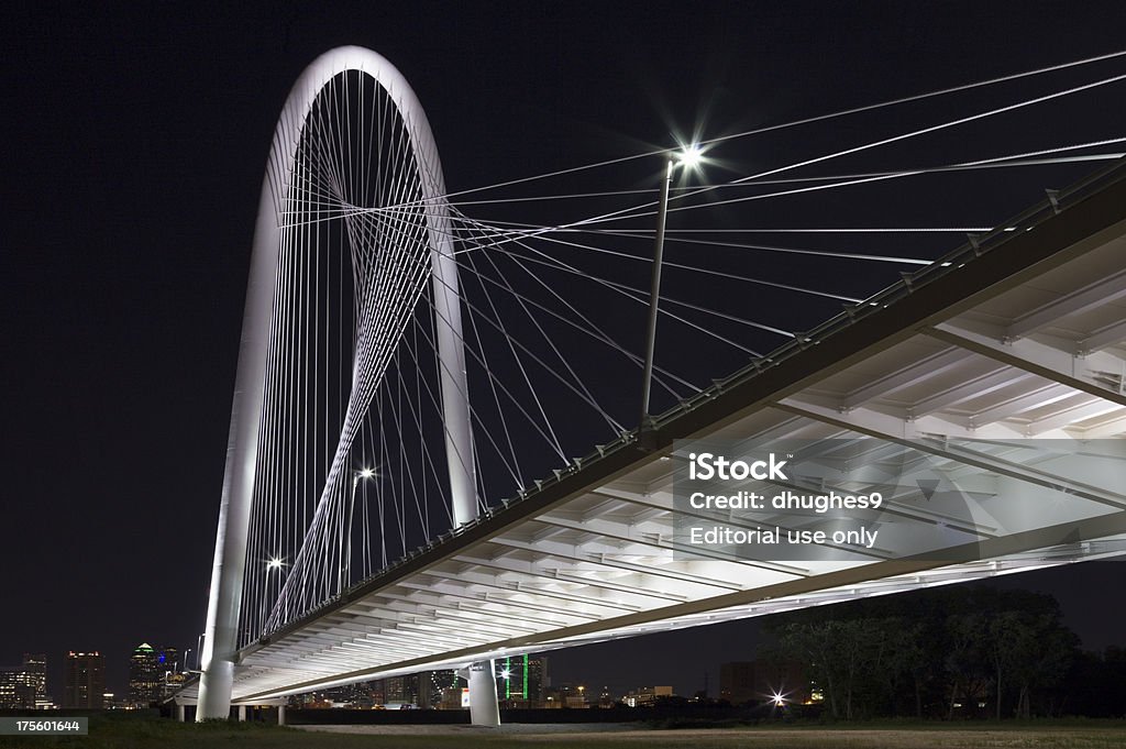 Dallas’ suspension bridge at night with city skyline background "Dallasaa new Margaret Hunt Hill Bridge over Trinity River, lit at night, with skyline buildings in background. This view shows lighted underneath sections of bridge." Dallas - Texas Stock Photo