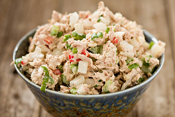 Tuna Salad A high angle close up shot of a blue ceramic bowl full of freshly made tuna salad. Shot on an old wooden background. seafood salad stock pictures, royalty-free photos & images