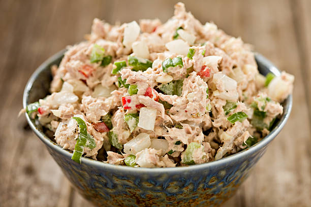 Tuna Salad A high angle close up shot of a blue ceramic bowl full of freshly made tuna salad. Shot on an old wooden background. fish in a bowl stock pictures, royalty-free photos & images