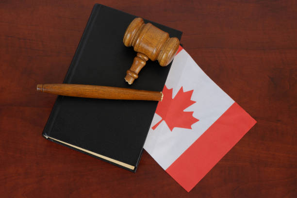 marteau cassé et livre juridique avec le drapeau du canada sur une table en bois. - canadian flag flag trial justice photos et images de collection