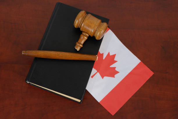 martelletto rotto e libro legale con bandiera del canada su tavolo di legno. - canadian flag flag trial justice foto e immagini stock