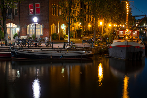 Netherlands. Summer night in Amsterdam. Canal embankment with houseboats and bicycles
