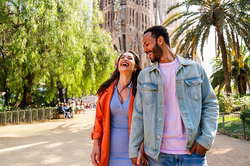 Multiracial beautiful happy couple of lovers dating at Sagrada Familia, Barcelona - Multiethnic tourists travelling in Europe and visiting a city in Spain, concepts about tourism and people lifestyle