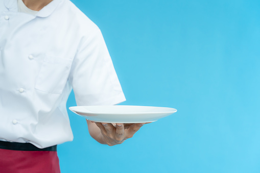 cooking, culinary, male chef holding empty plate, male chef in toque and jacket over blue background, professional, show, serve, cooking, , gourmet, food, service, restaurant, presenting