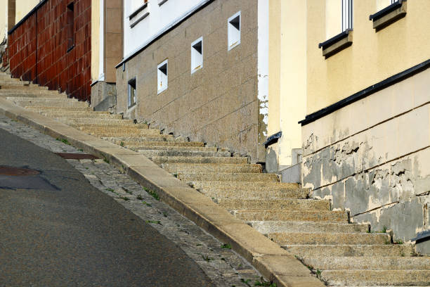 A steep street with staircase on sidewalk.