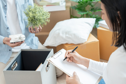 Move house, relocation. wife and husband record quantity furniture for new apartment, Inside the room are cardboard boxes containing personal belongings. Move into a house or condominium