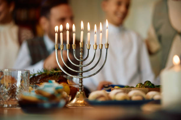 istock Lit menorah with family in the background during Hanukkah celebration. 1756055016
